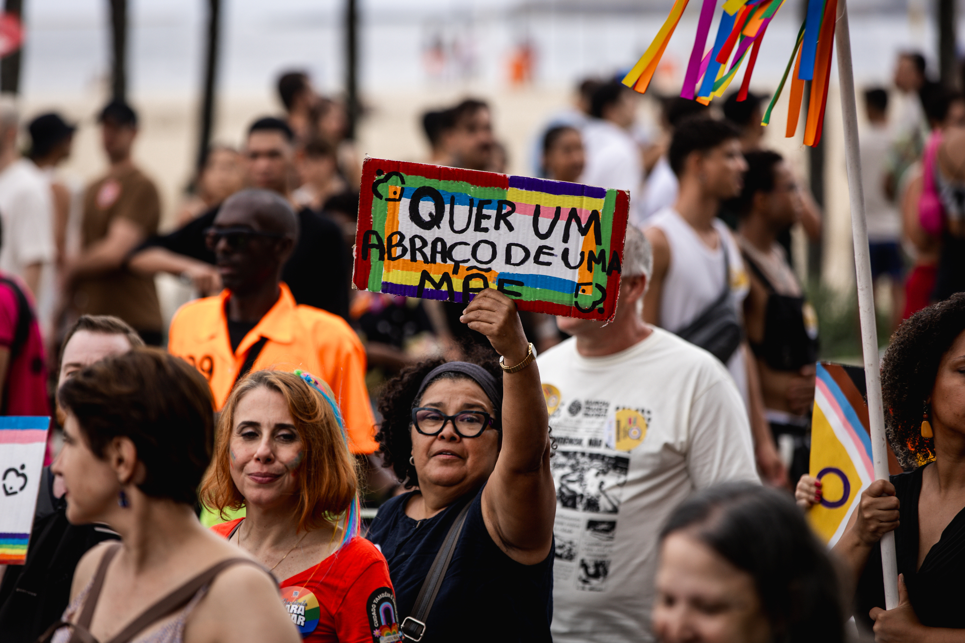 Público com cartaz colorido 'Quer um abraço de uma mãe?' durante a Parada