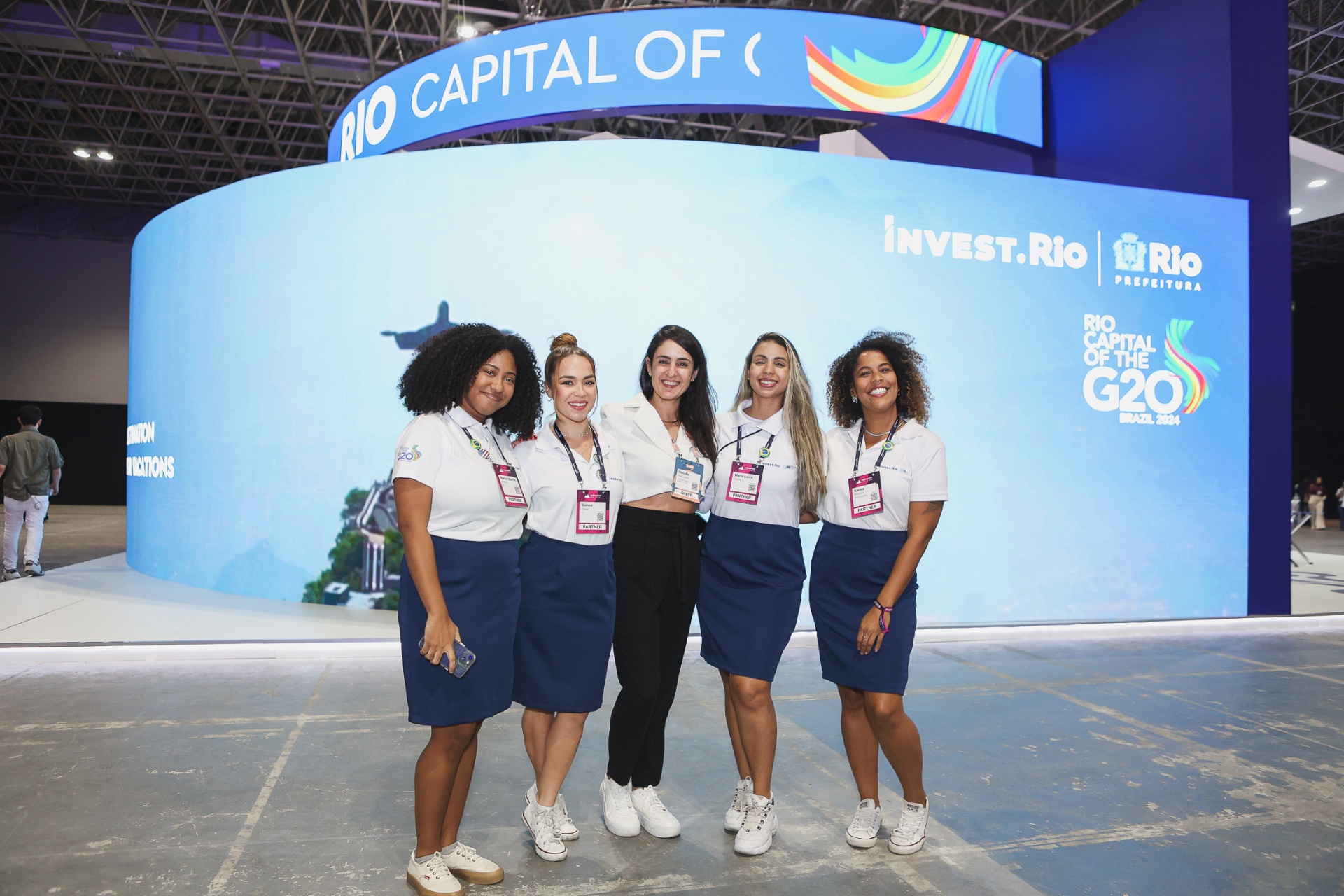 Equipe de atendimento em frente ao LED curvo Rio Capital of G20