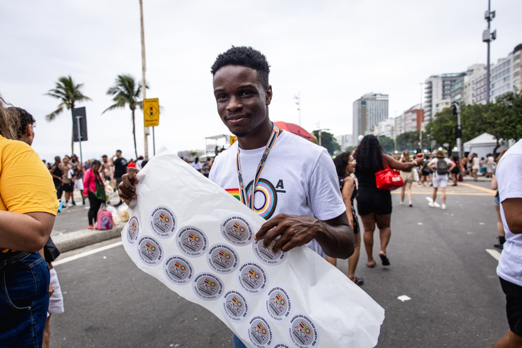 Colaborador distribuindo cartela de adesivos comemorativos dos 30 anos da Parada